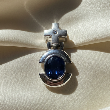 14K white gold oval blue sapphire and diamond cross bail pendant, front view