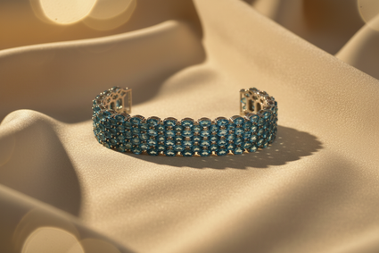 Sterling silver blue topaz wide cuff bracelet on cream satin, editorial luxury photography