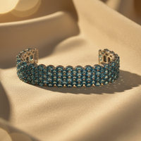 Sterling silver blue topaz wide cuff bracelet on cream satin, editorial luxury photography