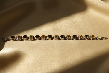 Sterling silver smoky quartz and citrine alternating link bracelet on cream satin, editorial luxury photography
