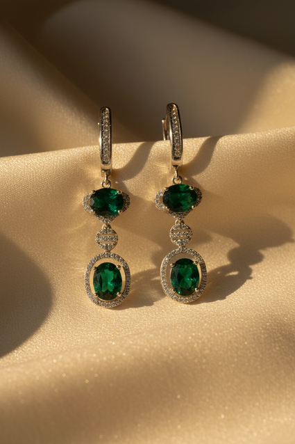 Sterling silver green emerald and white diamond double halo drop earrings on cream satin