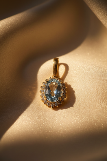 14K Yellow Gold Oval Aquamarine and Diamond Halo Enhancer Pendant - angled view on cream satin
