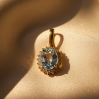 14K Yellow Gold Oval Aquamarine and Diamond Halo Enhancer Pendant - angled view on cream satin