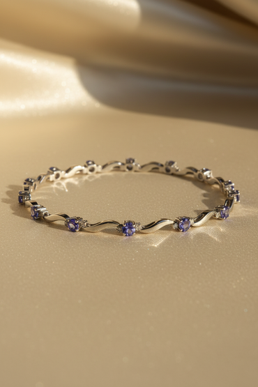 14K white gold tanzanite and diamond wave bracelet full length showing all 9 oval tanzanite stations with diamond accents