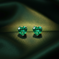14K White Gold GIA Colombian Emerald Heart Stud Earrings on forest green silk backdrop editorial marketing image