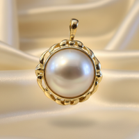 14K yellow gold mabe pearl enhancer pendant floating on cream satin backdrop with warm accent lighting