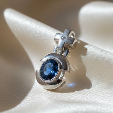 14K white gold oval blue sapphire and diamond cross bail pendant, three-quarter angle