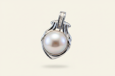 14K white gold mabe pearl and baguette diamond pendant floating on ivory backdrop luxury editorial marketing image