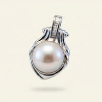 14K white gold mabe pearl and baguette diamond pendant floating on ivory backdrop luxury editorial marketing image