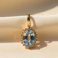 14K Yellow Gold Oval Aquamarine and Diamond Halo Enhancer Pendant - close-up detail on cream satin