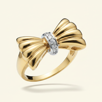 10K yellow gold diamond bow ring floating on ivory backdrop luxury editorial marketing image