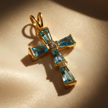 14K yellow gold cross pendant with baguette-cut blue topaz arms and round brilliant diamond center, angle 1