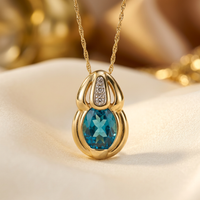 14K yellow gold blue topaz and diamond pendant, front view on cream satin