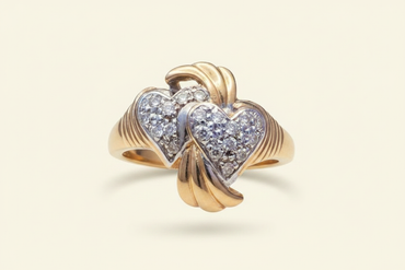 10K yellow gold double heart diamond ring floating on ivory backdrop luxury editorial marketing image